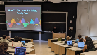 Audience listening to a presentation titled "How to find new particles, really fast" in an auditorium